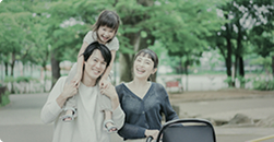 公園で子どもを抱っこしながら笑顔で過ごす家族の様子