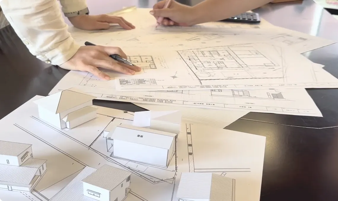 設計図と模型を机の上に広げている写真